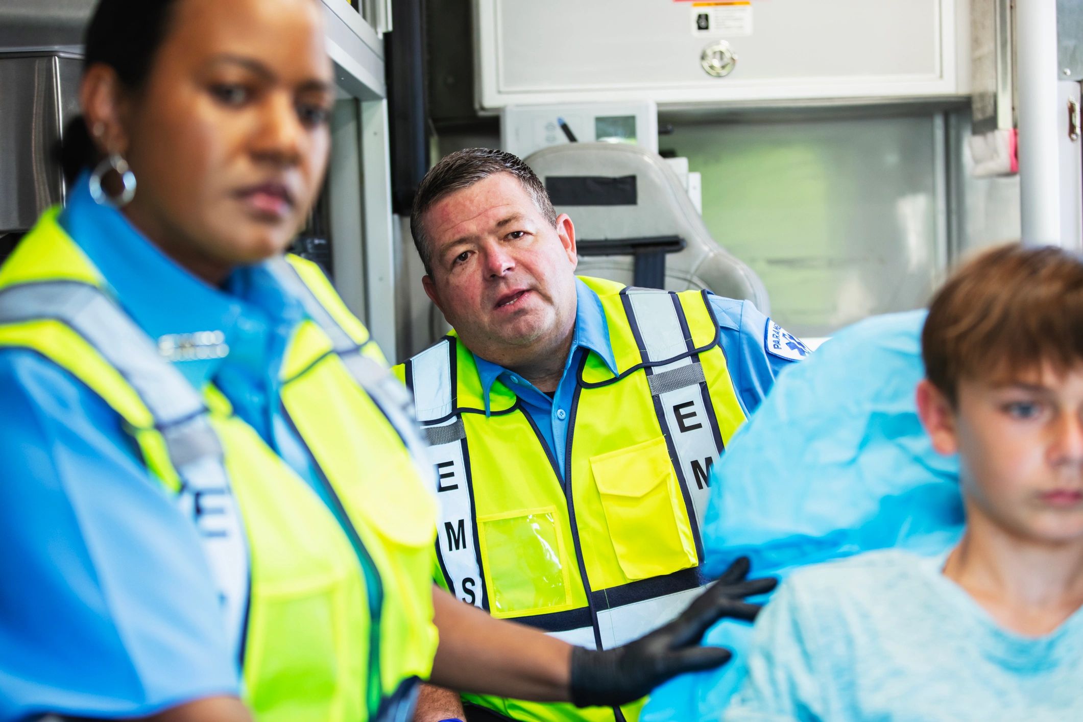 Paramedics coordinating patient care inside an ambulance during transport