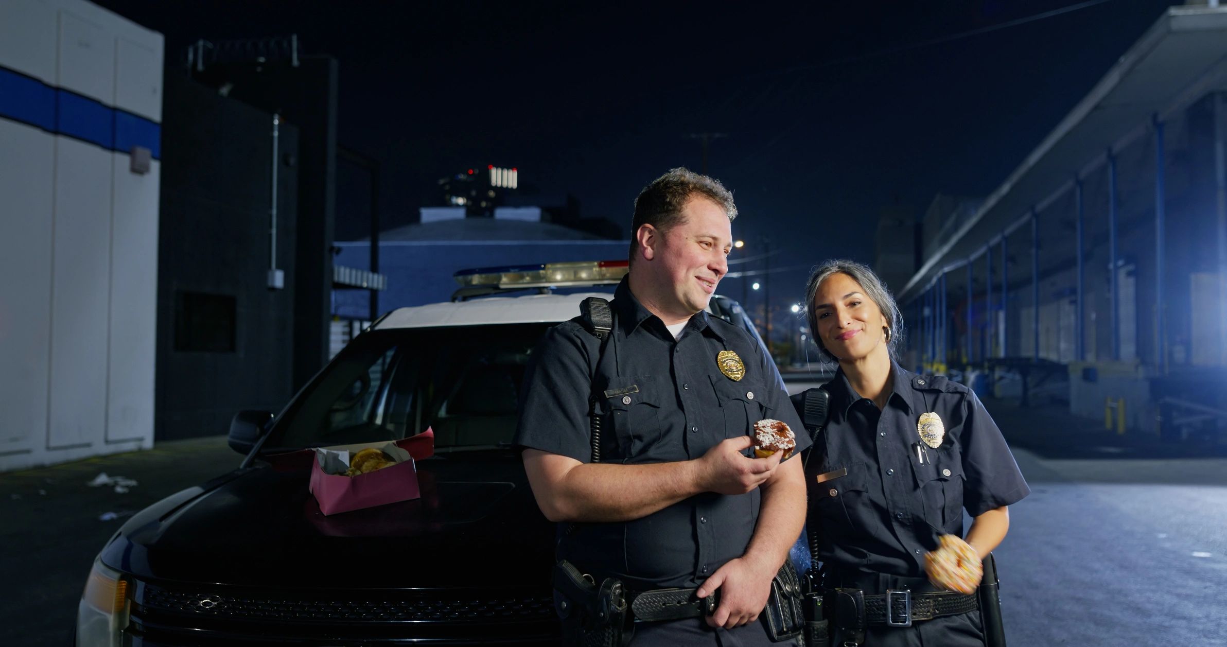 Two police officers beside a patrol car during a night shift break.