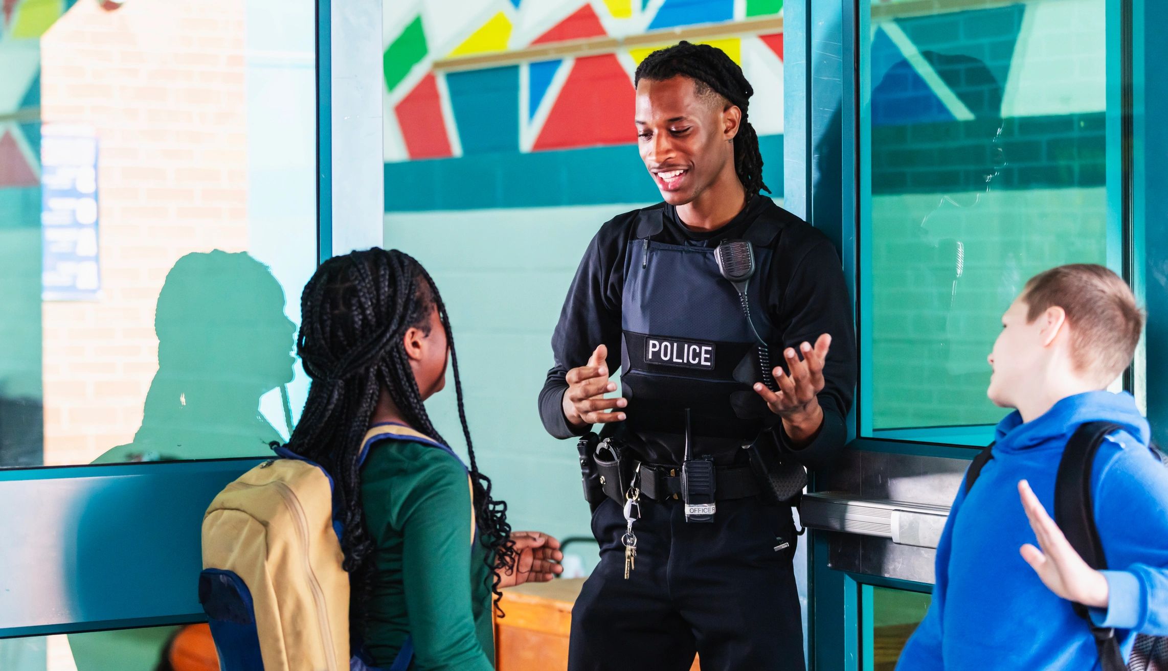 School resource officer greeting students at a school entrance.